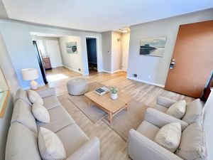 Inviting living room with modern decor, featuring a comfortable sofa, stylish armchairs, and a sleek coffee table on warm wood flooring.