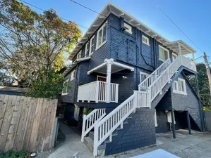 Charming blue townhouse with a modern exterior, showcasing a welcoming porch and elegant staircase, nestled in a serene neighborhood.