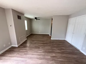 Modern living area with sleek hardwood floors, neutral walls, and ample natural light, perfect for stylish interiors.