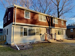 Charming two-story house with warm wooden accents and welcoming front porch, set in a tranquil suburban neighborhood.