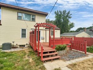 Charming backyard with a red wooden deck and pergola, perfect for outdoor gatherings and relaxation.