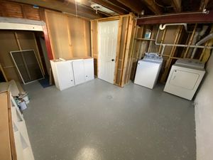 Spacious laundry room with washer and dryer, fresh painted floor, and ample storage space.