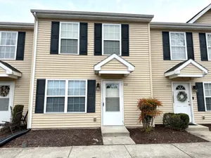 Inviting townhouse facade with beige siding and black shutters.