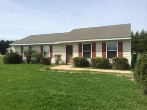Charming single-story home with a cozy exterior, featuring red shutters and a neatly landscaped front yard.