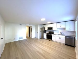 Bright, modern kitchen with stainless steel appliances, sleek white cabinetry, and elegant wood flooring, offering a spacious and welcoming environment.