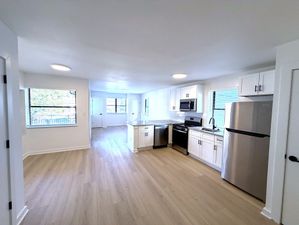 Bright, open-concept kitchen and living area with sleek stainless steel appliances and modern white cabinetry.