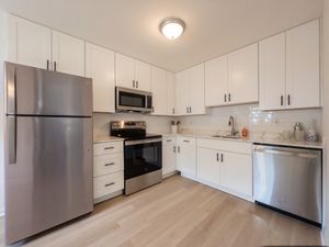 Modern kitchen with sleek stainless steel appliances, elegant white cabinetry, and stylish light wood flooring.