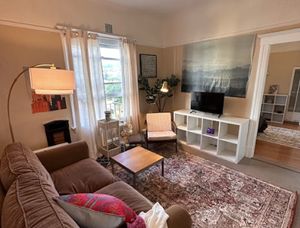 Inviting living room with a cozy couch, stylish rug, and natural light from a large window, perfect for relaxation and entertainment.