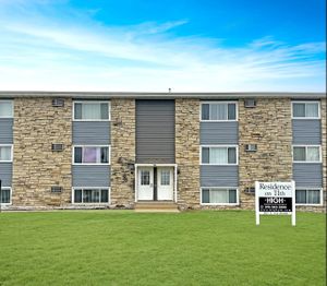 Inviting apartment building with a modern stone facade and lush green lawn, welcoming entrance at Residence on 11th.
