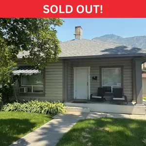 Charming single-story home with cozy front porch, nestled amidst lush greenery and mountain views. Marked as sold out.