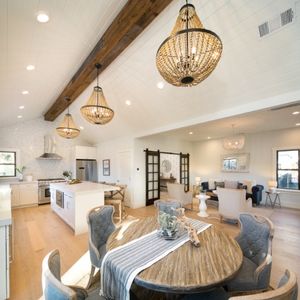 Elegant open-concept living area with vaulted ceilings, featuring a modern kitchen and cozy dining space illuminated by chic chandeliers.