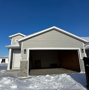 Charming single-story home with a spacious garage, set against a crisp blue sky and surrounded by fresh winter snow.