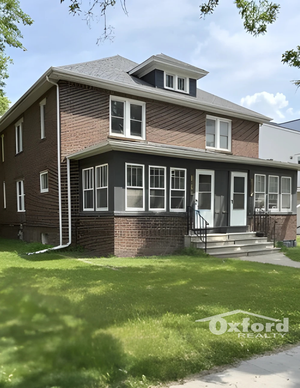 Charming two-story brick home with a classic design, large windows, and a well-maintained front lawn, perfect for family living.