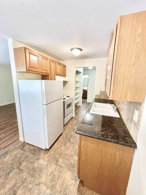 Charming kitchen with granite countertops, wooden cabinets, and modern appliances in a cozy apartment.