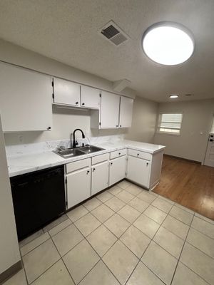 Modern kitchen with sleek white cabinets, dual sinks, and elegant tile flooring, perfect for culinary creativity.