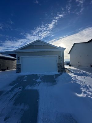 Charming single-story home with a two-car garage, set against a stunning winter sky.