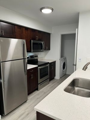 Modern kitchen featuring stainless steel appliances, sleek cabinetry, and an adjacent laundry area with contemporary flooring.