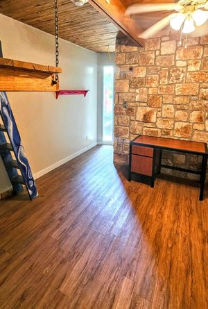 Charming room with rustic stone accent wall, stylish wooden ceiling, and sleek laminate flooring, offering a cozy and inviting atmosphere.