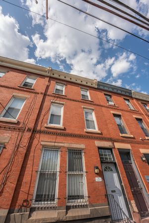 Charming urban red brick townhouse with elegant architecture and large windows under a bright blue sky.
