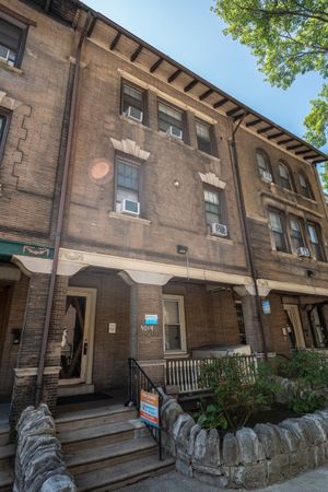 Charming brick apartment building with classic architecture, inviting steps, and a small garden space in front.