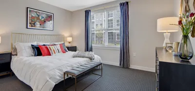 Contemporary bedroom with elegant decor, featuring a plush white bed, chic nightstands, and a large window flooding the space with natural light.