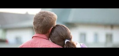 Couple embracing with a view of cozy suburban homes, conveying warmth and a welcoming neighborhood atmosphere.