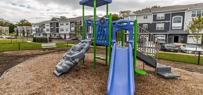 Charming residential area with modern apartments and a colorful playground featuring slides and climbing structures.