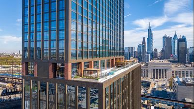 Modern high-rise building with sleek glass facade and luxurious rooftop terrace, set against a vibrant city skyline.