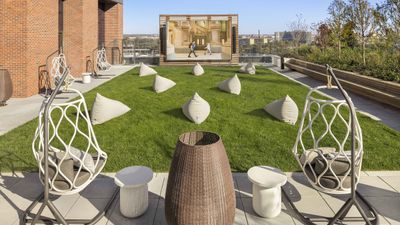 Luxurious rooftop garden with stylish egg chairs, lush grass, modern outdoor seating, and panoramic view.