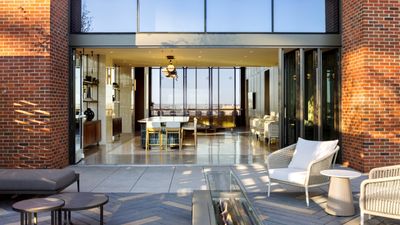 Modern open-concept apartment with expansive glass walls, cozy outdoor seating, and elegant indoor dining area.