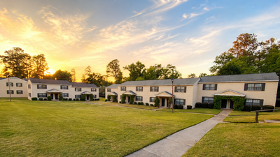 Charming row of apartment buildings with manicured lawns and a picturesque sunset, perfect for serene living.