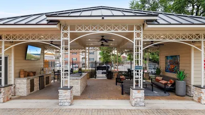 Charming outdoor pavilion with modern grill station, stylish seating, and lush greenery, perfect for entertaining.