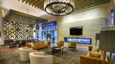 Elegant and spacious living room with modern decor, featuring a large chandelier, cozy seating area, and a stylish fireplace.
