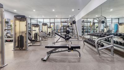 Modern gym with state-of-the-art fitness equipment, mirrors, and ample lighting for an energizing workout experience.