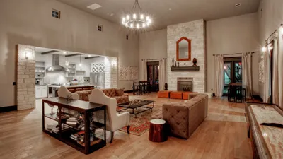 Inviting open-concept living space with elegant stone fireplace, stylish seating, and modern kitchen in a chic apartment.