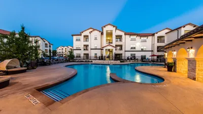 Luxurious apartment complex at dusk featuring a beautifully illuminated outdoor swimming pool surrounded by chic modern architecture.