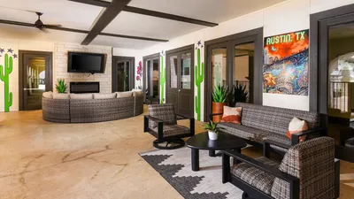 Chic patio lounge with stylish wicker seating, vibrant wall art, and lush greenery in an Austin, TX setting.