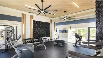 Modern fitness center featuring sleek exercise machines, free weights, and elegant wood ceiling design.