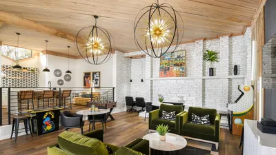 Chic open-concept living space featuring plush green velvet seating, contemporary lighting, and a stylish kitchen with bar seating.