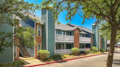 Modern apartment complex with vibrant surroundings, featuring stylish architecture, lush greenery, and inviting balconies.