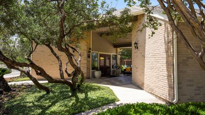 Inviting entrance to an elegant apartment complex, framed by lush trees and vibrant greenery, highlighting serene outdoor spaces.