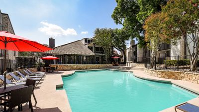 Inviting outdoor pool area with sun loungers, vibrant red umbrellas, and lush greenery, ideal for relaxation and leisure.
