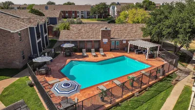 Inviting outdoor swimming pool surrounded by stylish lounge chairs and vibrant green landscaping, perfect for relaxation and leisure.