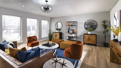 Elegant living room with chic modern decor, featuring plush velvet chairs, stylish lighting, and large windows overlooking a serene outdoor view.
