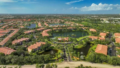 Breathtaking aerial view of a serene residential community with pristine lakes, lush greenery, and charming terracotta-roofed homes, perfect for tranquil living.