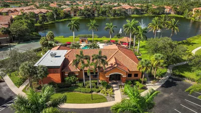 Luxury apartment complex with a beautiful lake view, palm trees, and a resort-style pool area, offering a serene and upscale living experience.