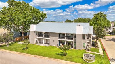 Charming apartment complex with modern exterior, lush green surroundings, and inviting balconies under a vibrant blue sky.