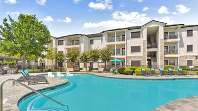 Luxurious apartment with a sparkling turquoise pool surrounded by stylish lounge chairs and vibrant greenery.