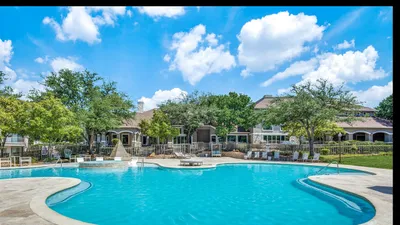 Inviting residential pool area featuring crystal-clear water, elegant lounge chairs, and lush landscaping under a bright blue sky.