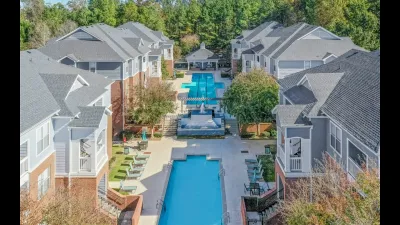 Charming apartment complex featuring modern gray roofing, a stunning central swimming pool, and lush greenery.